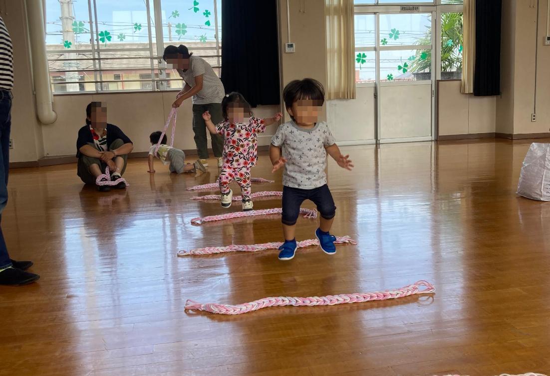 並べた紐でジャンプ遊びをする幼児の写真
