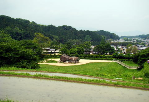 山に囲まれ広く開けたところにある、いくつもの大きな岩が重なったり並んでできた石舞台古墳の写真