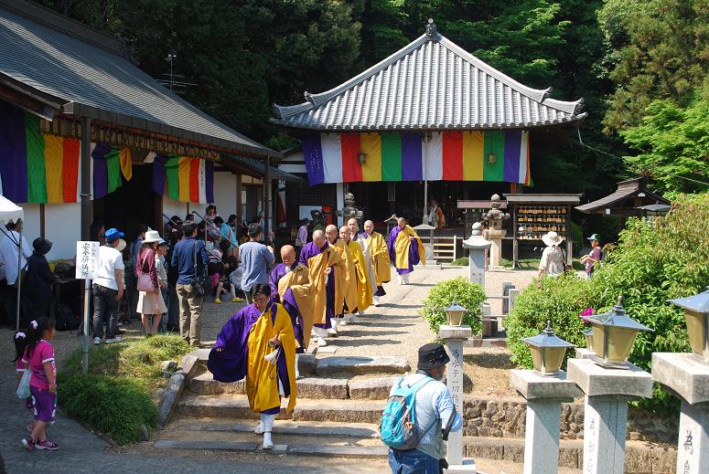 黄色い袈裟を着たお坊さんが行列になってお寺から歩いてくる写真