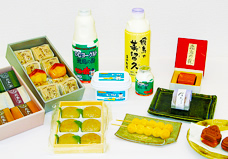 パッケージされた商品や、お皿に盛られたおだんごなど美味しそうな銘菓が机に並べられている写真
