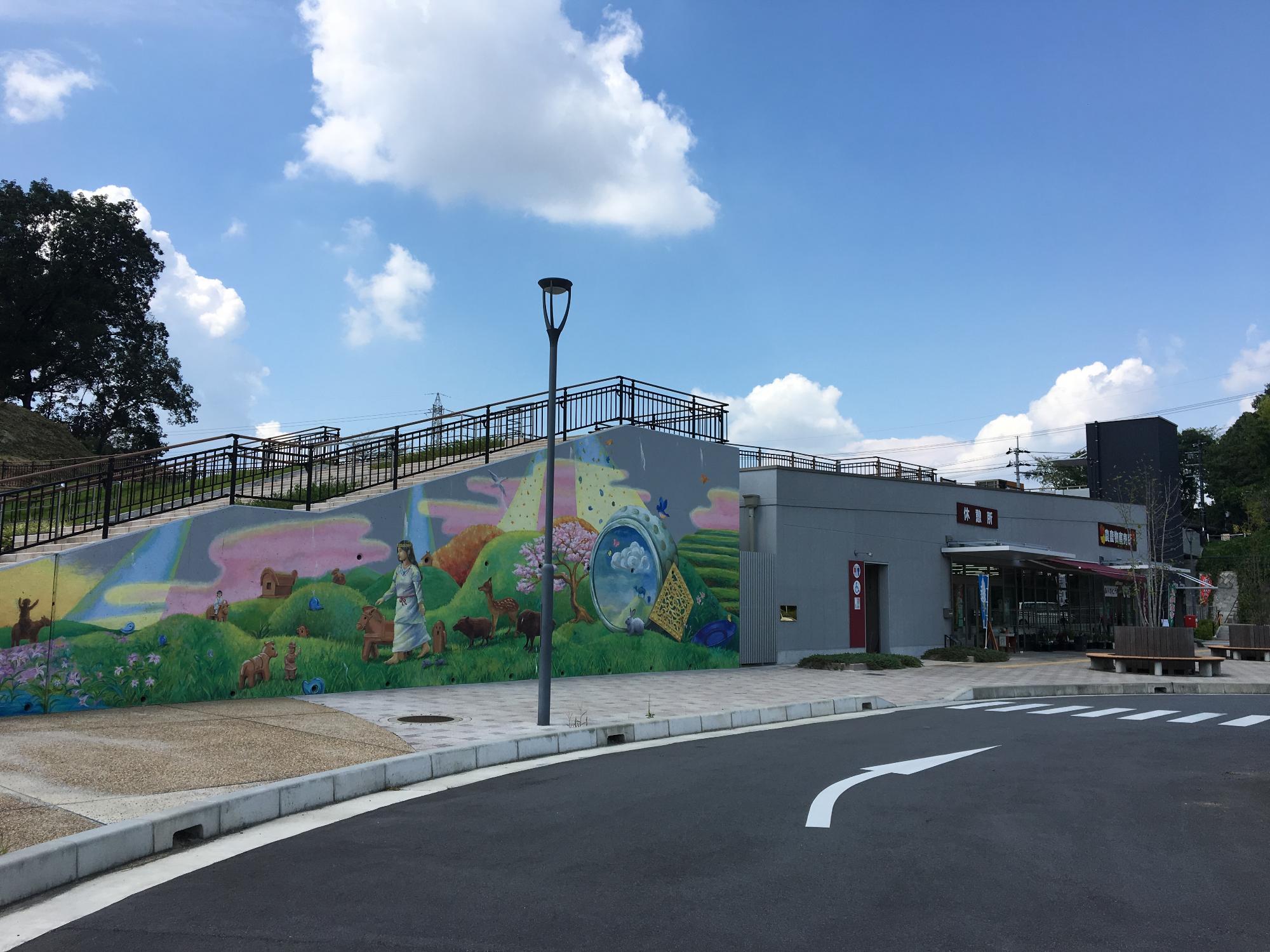 壁に女性が野原を歩いてる絵が描かれている新沢千塚ふれあいの里の外観の写真