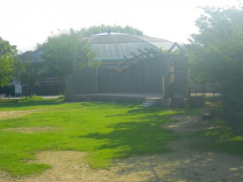 中央に写された、燦々と輝く太陽の下で周りを新緑が彩る木製ステージの写真