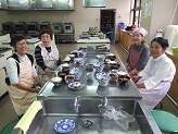 講師と参加者がテーブルに並べられた献立を前にイスに座っている写真