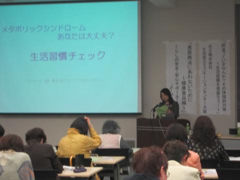 スクリーンに生活習慣チェックと写っていて、横で管理栄養士さんが聴衆の前で話している写真