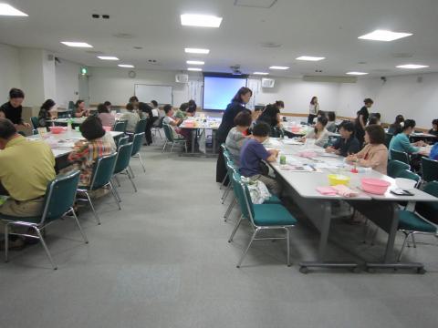 会議室で大勢が机を囲んで作業をしている写真