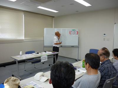 ホワイトボードを使って話をする講師と話を聞く人々の写真