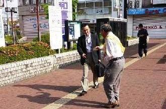 街頭で街頭啓発活動を実施している男性と、通りかかった男性の写真