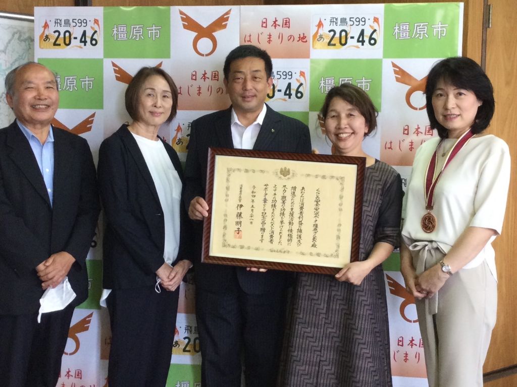 五人の男女が並んで一人の男性と一人の女性が一緒に賞状を持っている写真