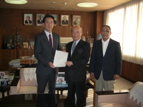 亀田市長とその左側で答申の紙を持ち合う川上会長と米田副会長の写真