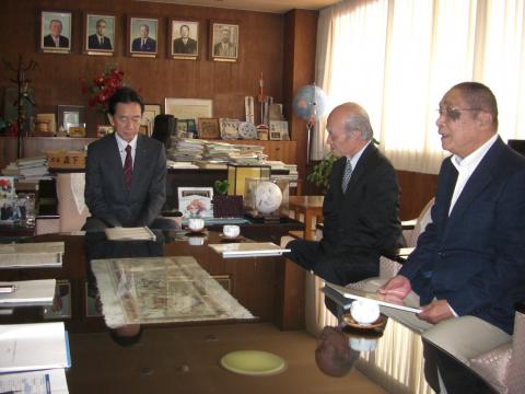 テーブルを囲んで川上会長と米田副会長から答申を受ける亀田市長の写真