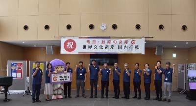 国内推薦を祝福する横断幕の下で記念撮影する橿原市長と職員の写真