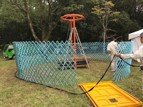 芝生の上で男性二人が建物の骨組みを作っている写真