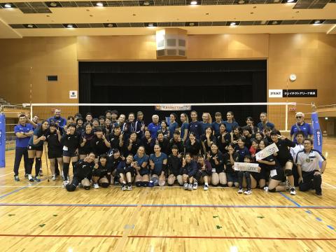 ステージのカーテンが閉まっている前で男女が写っている集合写真