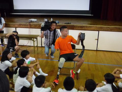 池田選手がイスに座って小学生に説明をしている写真