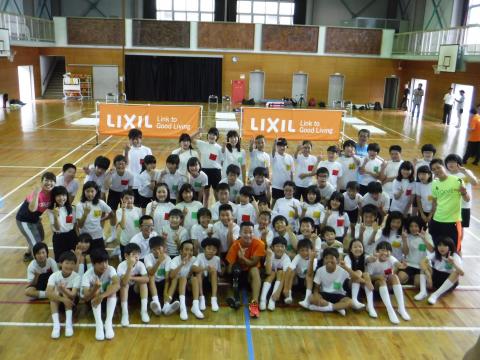 池田選手と小学生達がリクシルの旗の前に集まって撮った集合写真