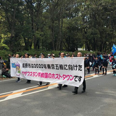 大きな横断幕を持った大人5人が沿道でパレードしている写真