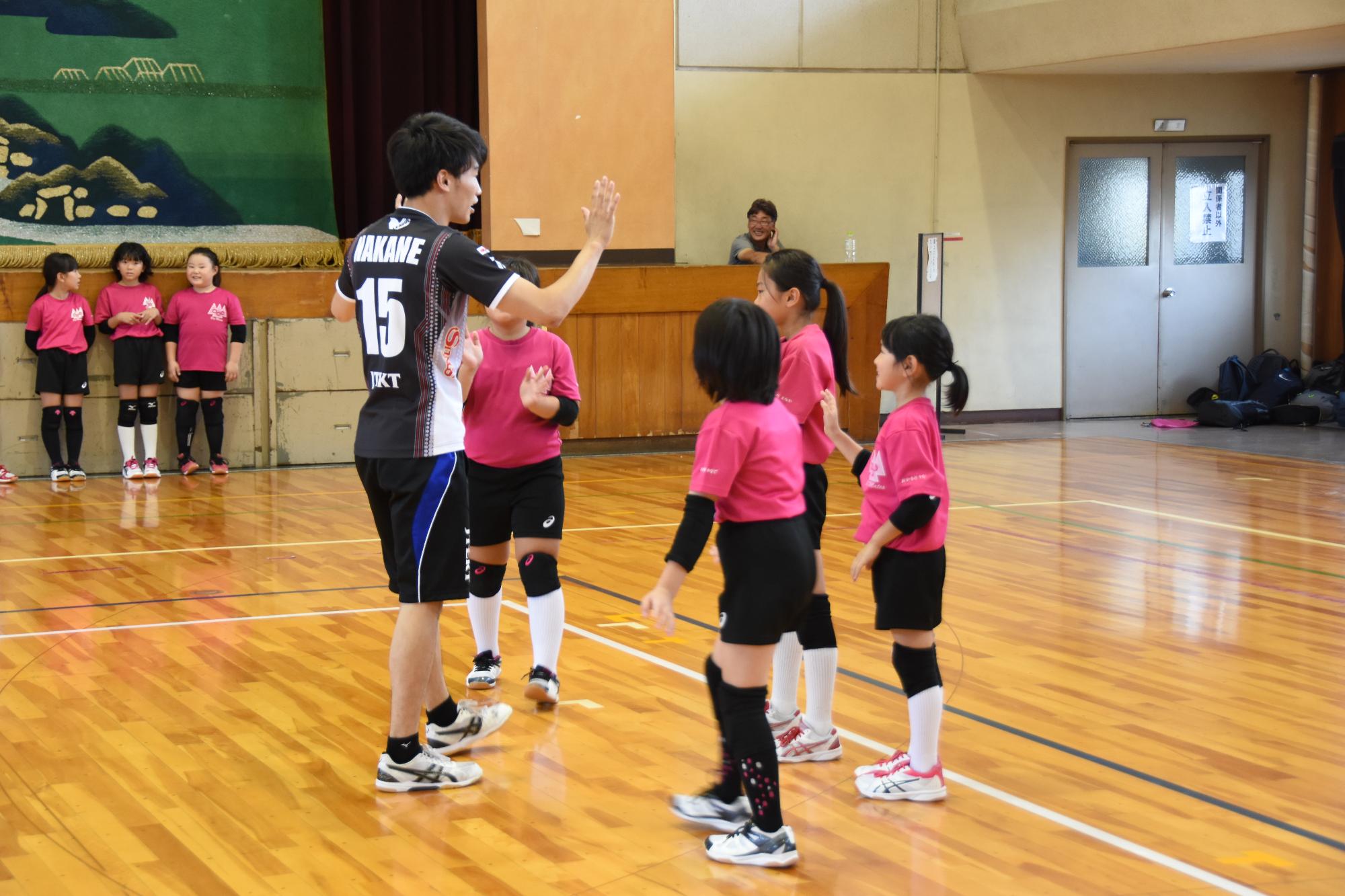 選手が体育館で4人の女子生徒にレクチャーをしている写真