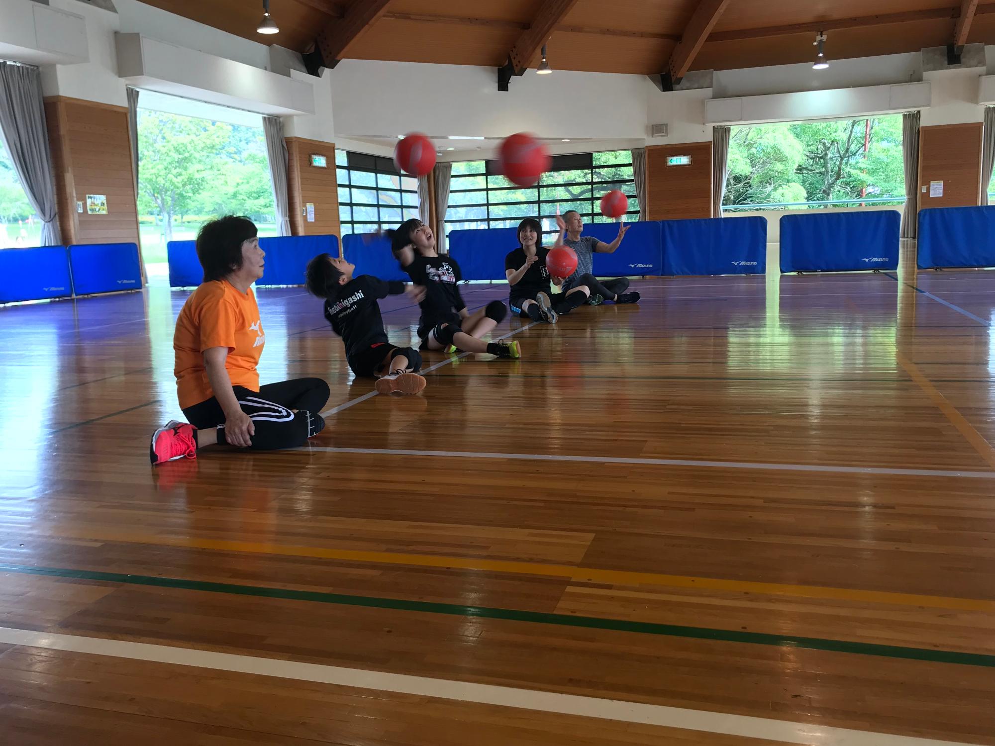 ボールを真上に投げて座っている参加者の写真