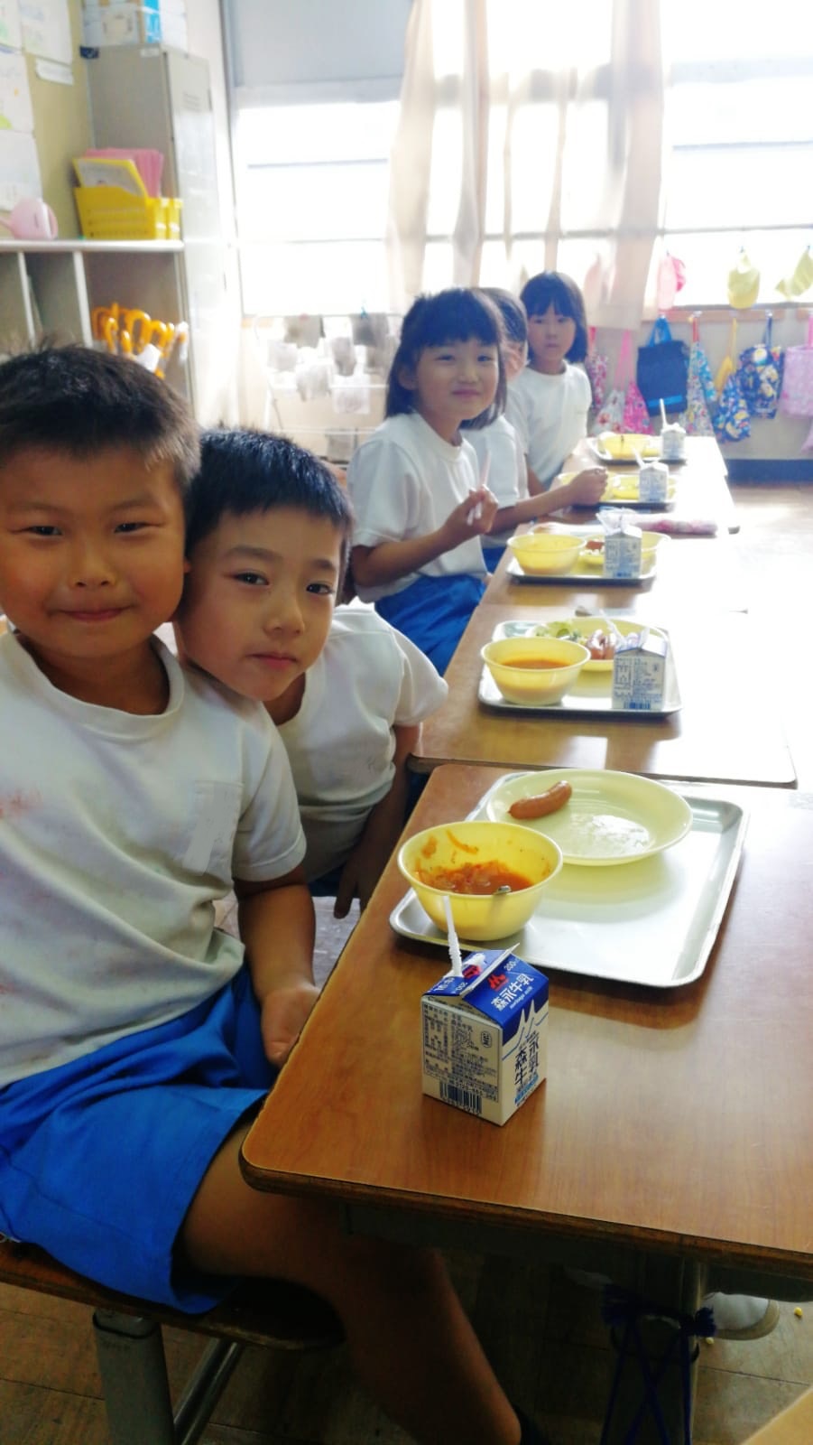美味しそうに給食を食べる5人の子供たちの写真
