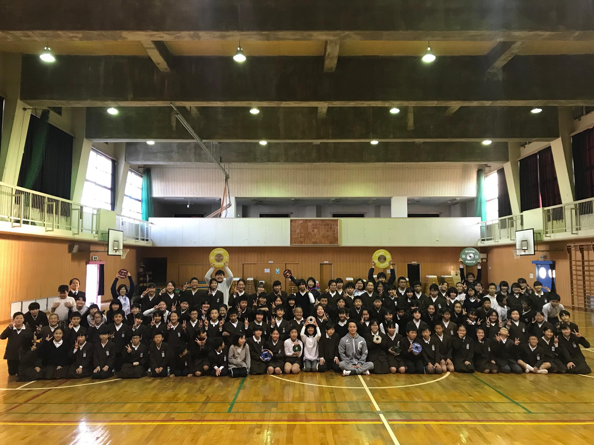 車椅子の選手と多くの児童の集合写真