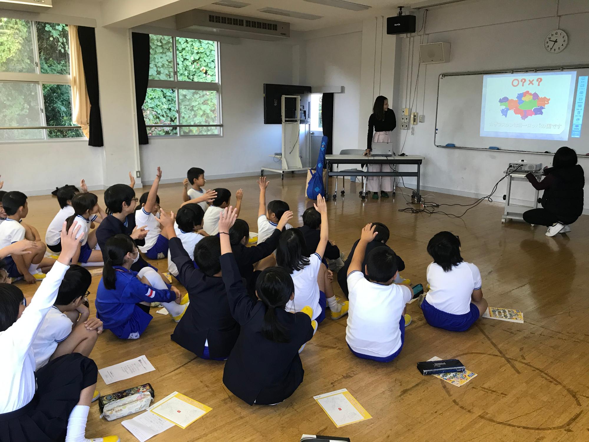 カザフスタンの国際交流員が白橿南小学校の生徒達に向けて国際理解教育授業を行いっている写真