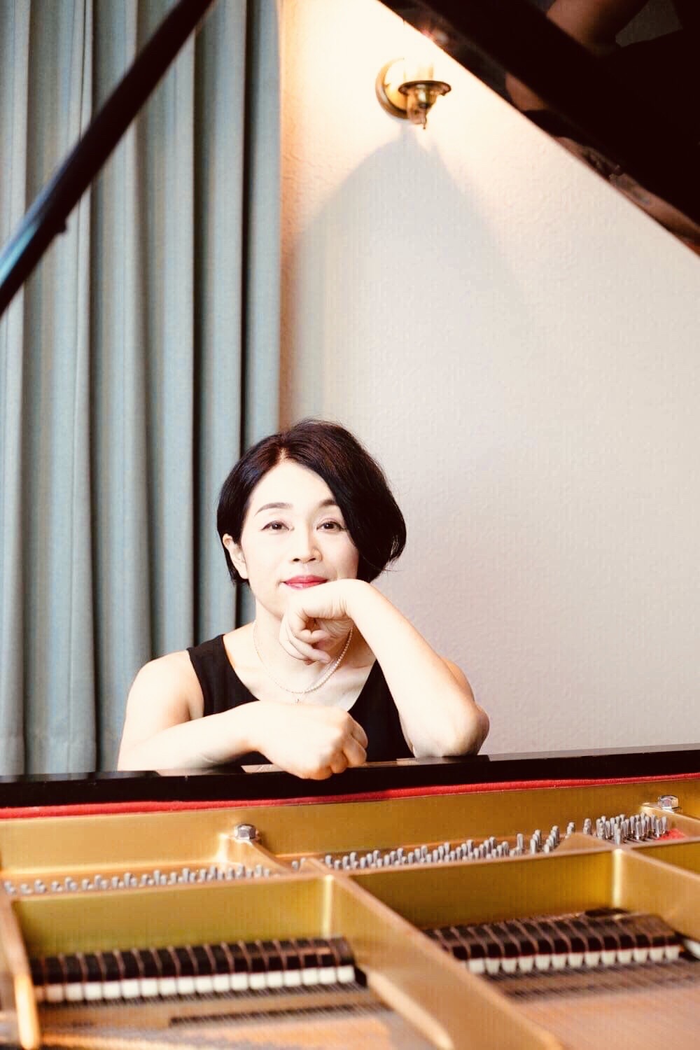 グランドピアノと共に写る辻ゆり子氏の写真