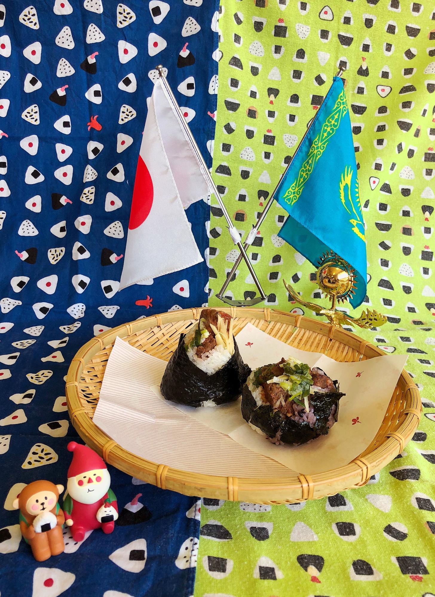 日本とカザフスタンの国旗が立ててあるザルの上にシャシリクにぎりが二つ置いてある写真