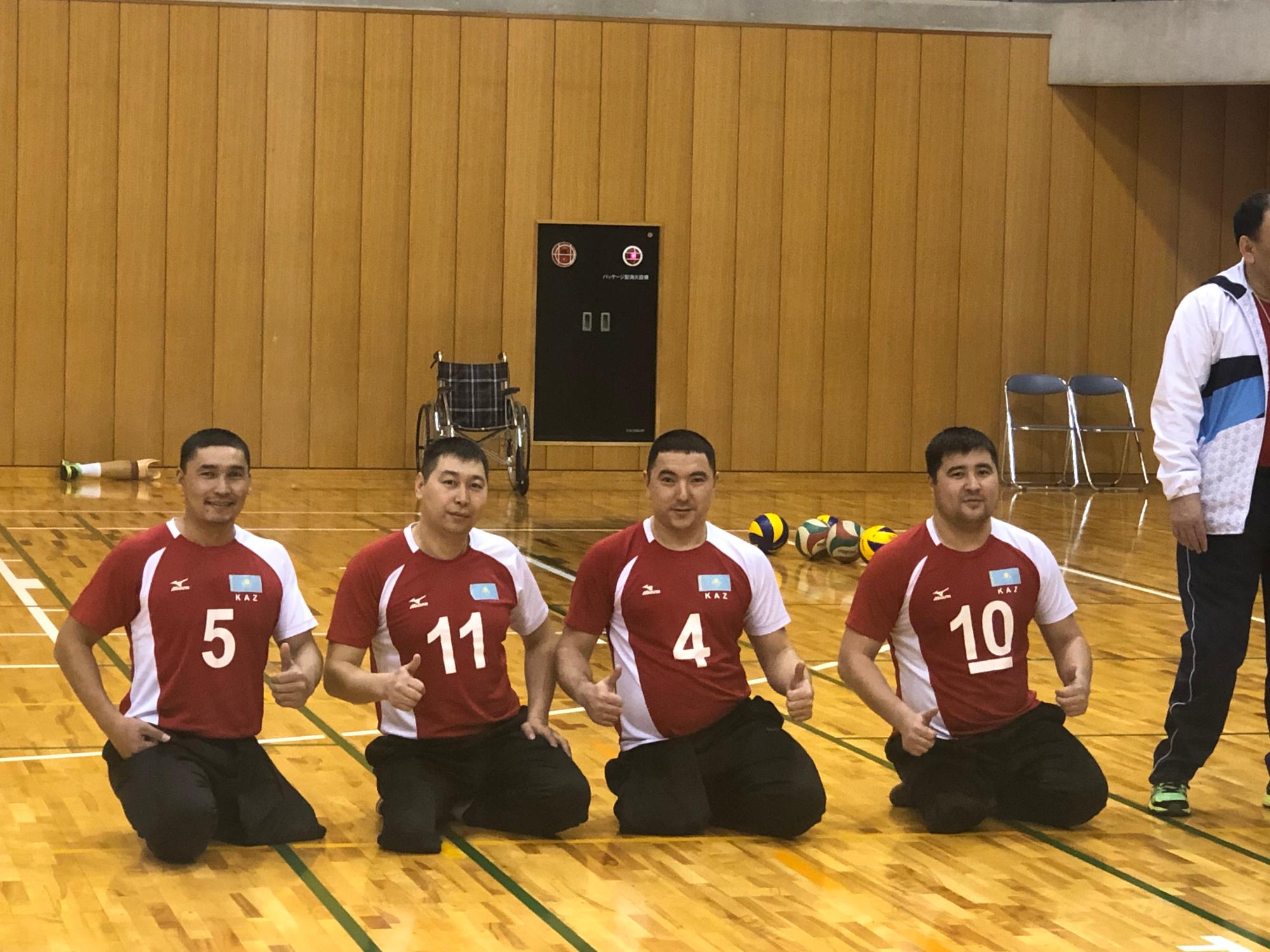 カザフスタン男子シッティングバレーボールナショナルチーム4名が親指を立てるポーズをとっている写真