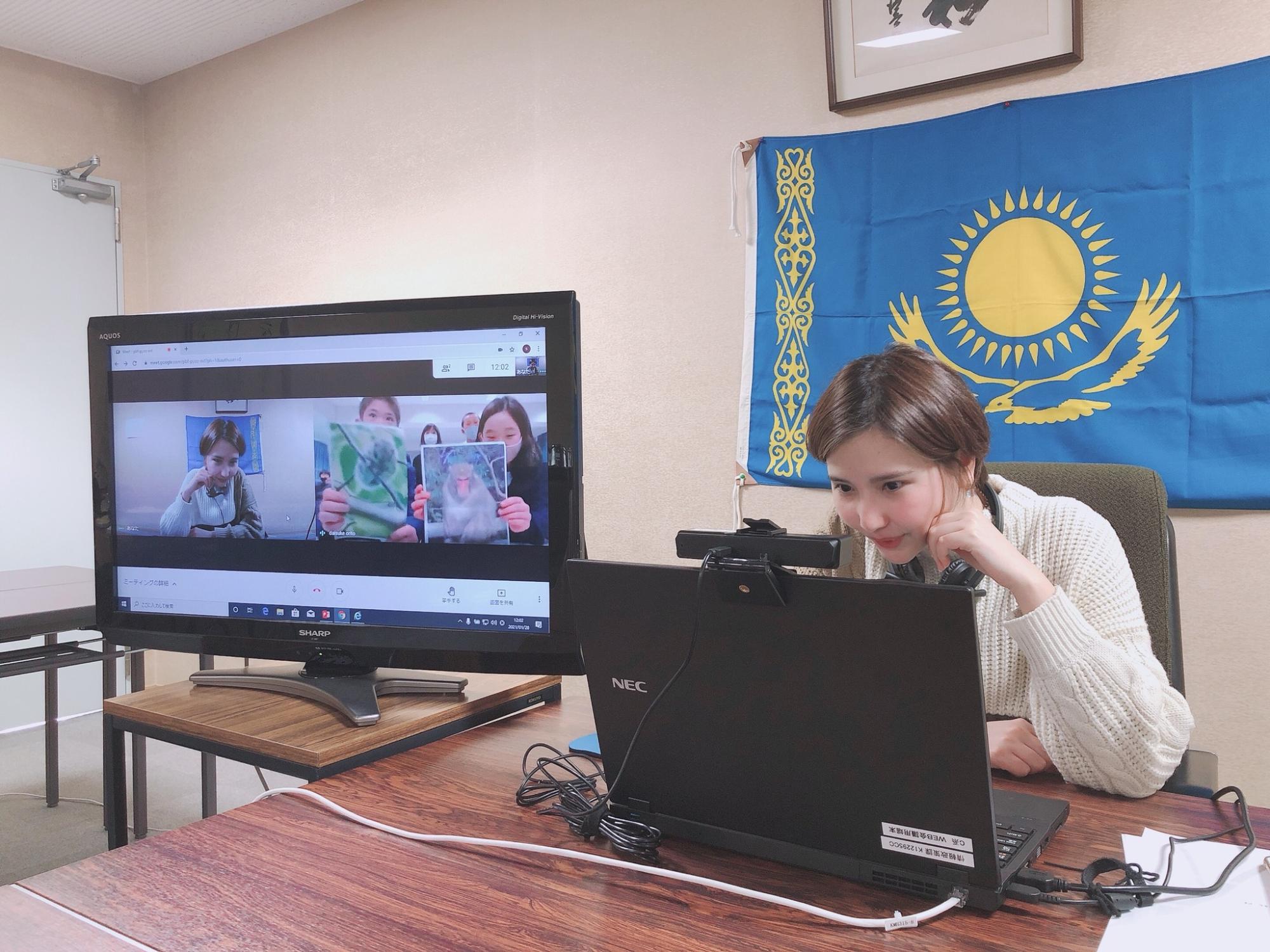 数人のグループの子供たちが女性に様々な写真を見せて日本の文化について紹介している様子の写真