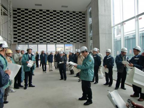 建設中の観光交流センターの中でヘルメットをかぶって説明を受ける議員達の写真