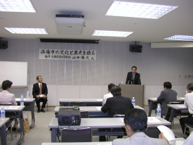 議員達の前で意見を述べる議員とそれを聞いている山田勝久氏の写真