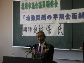 講演台の前に立つ地村保氏の写真