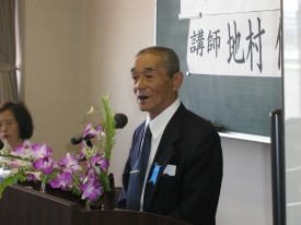 講演台の前で講義を行う地村保氏の写真