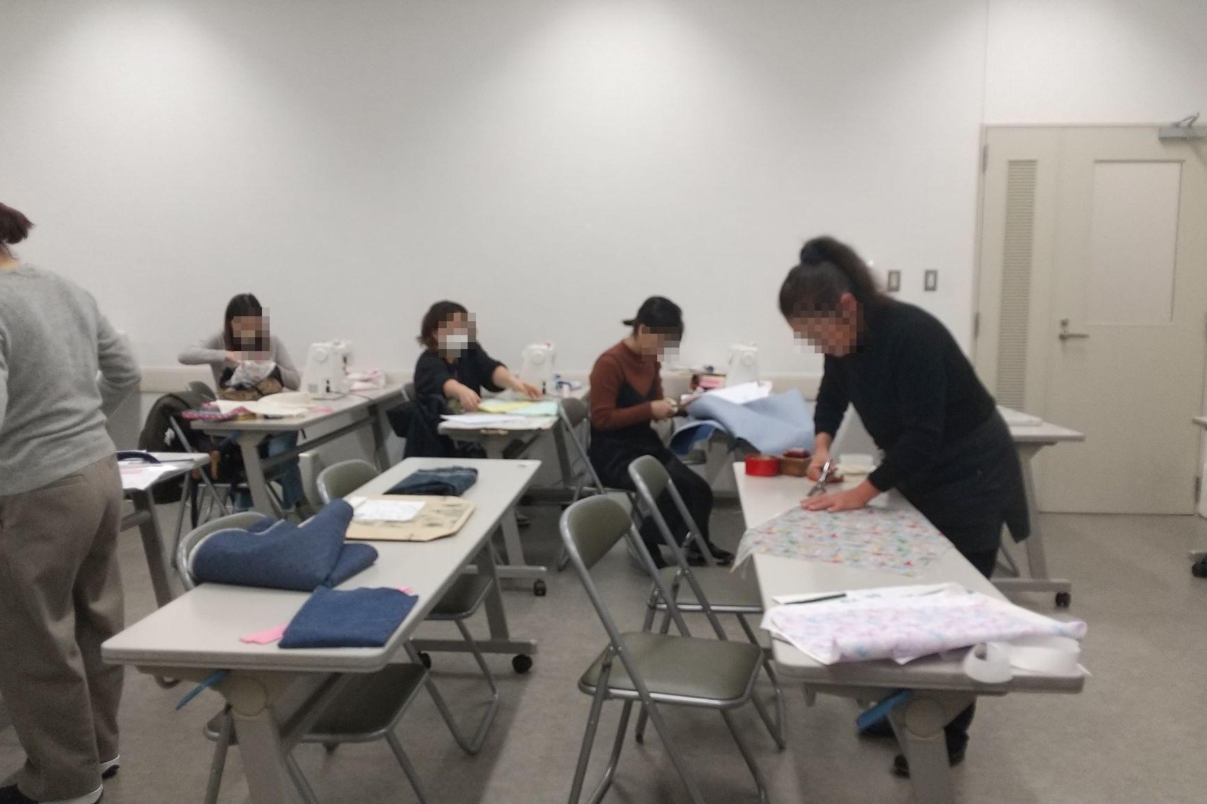 来年度の入学に向けて通園グッズを作る保護者たちの写真