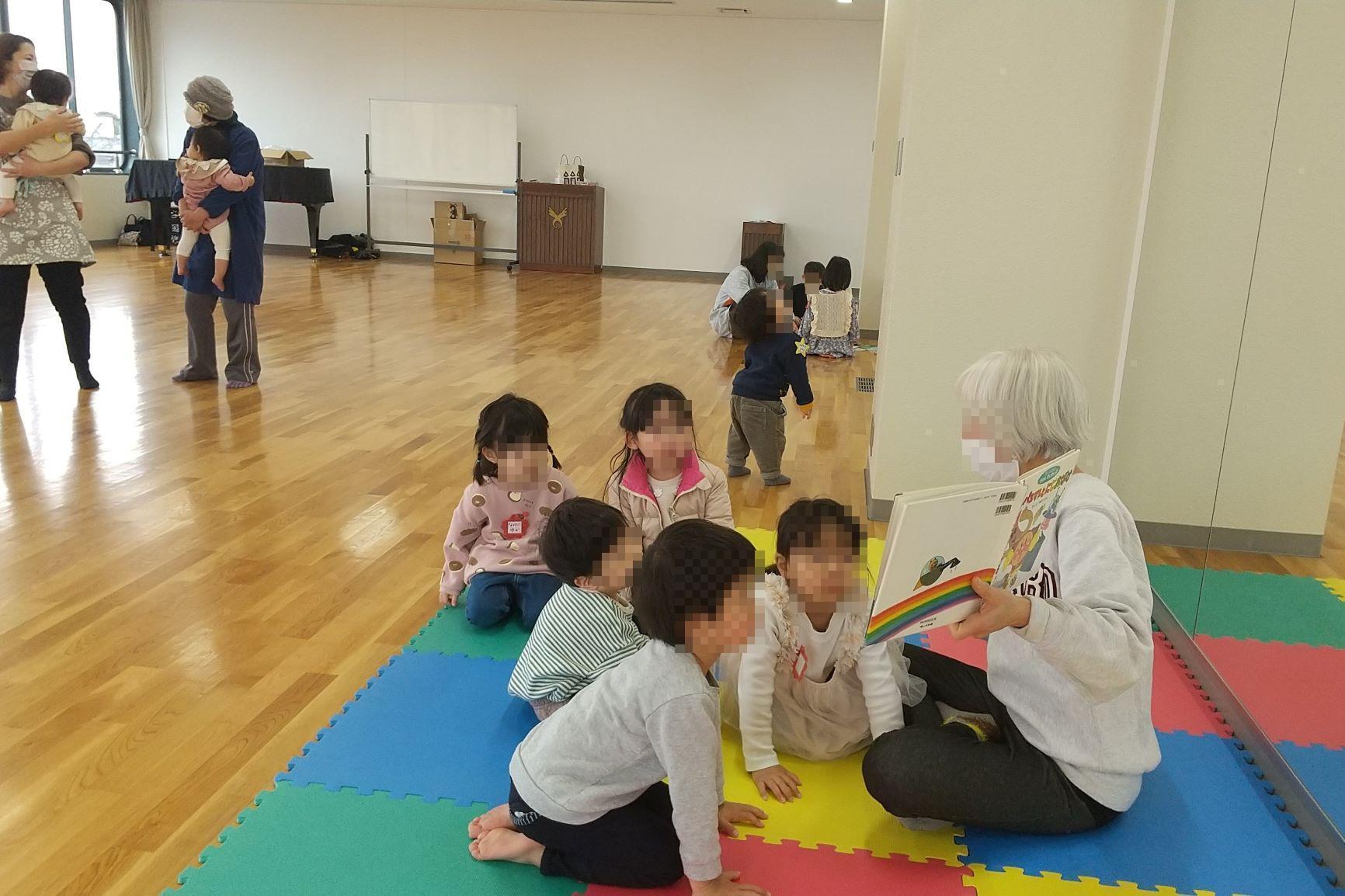 保護者と離れて絵本の読み聞かせを楽しむ幼児達の写真
