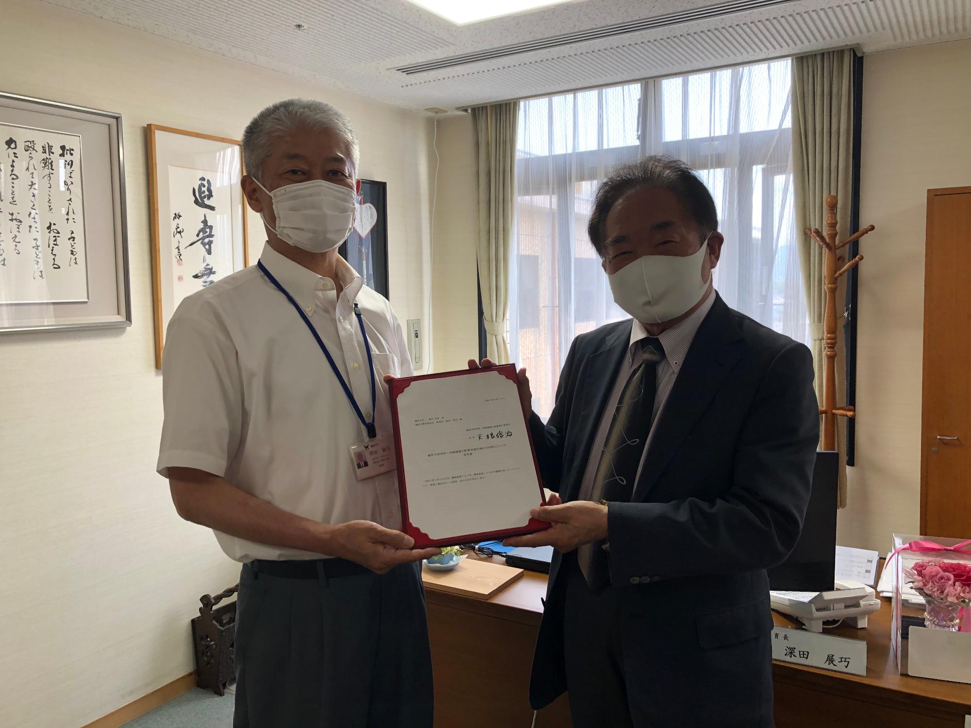 室内で答申書を二人で手に持ち笑顔の天根会長と深田教育長の写真