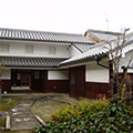 植木と飛び石があるL字型の瓦屋根住居の玄関前の写真