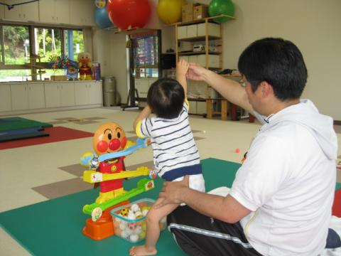 機能訓練室内で子どもの理学療法を行っている男性の理学療法士の写真