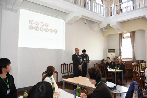 未来カフェ内で主催者が参加者の前でワークショップの挨拶をしている様子の写真