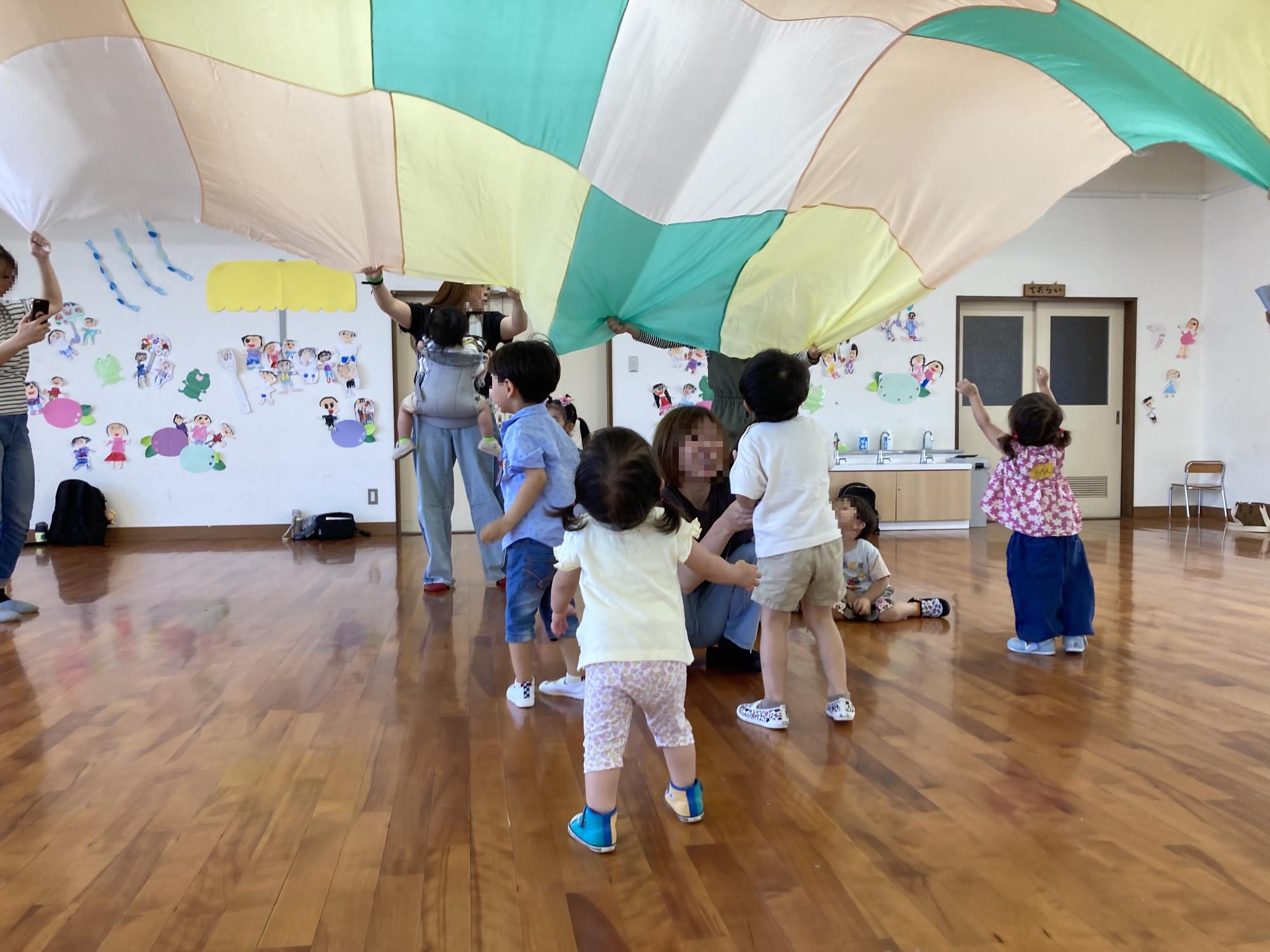 パラバルーンで遊ぶ幼児達の写真