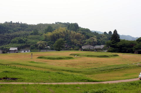 奥に山があり草原の真ん中が少し盛り上がっている様子の山田寺跡の写真