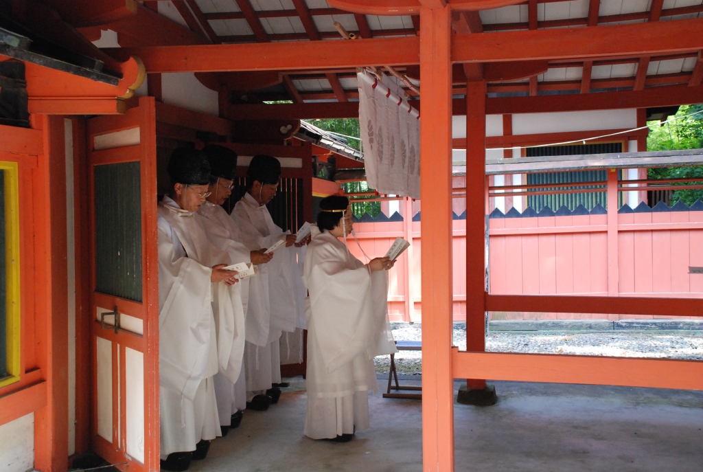 白い袴を着た4人の神官が神殿の入り口に立ち祝詞をとなえている様子の写真