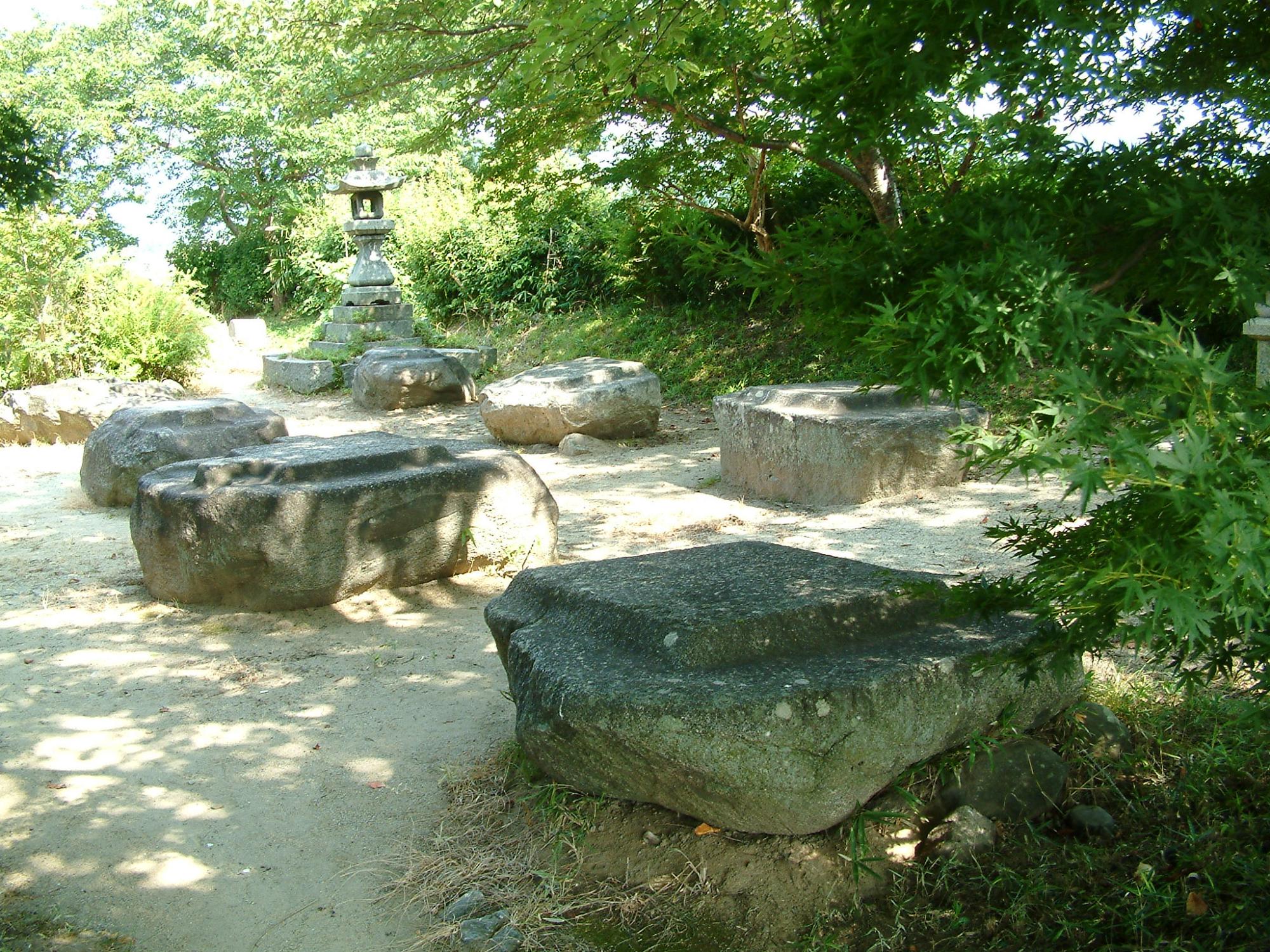緑の茂る中で岩のベンチが6つと石の灯籠が置かれた敷地の写真