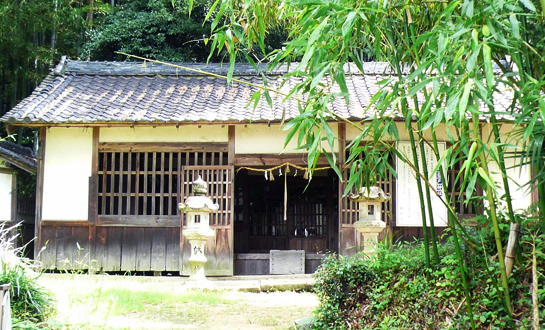 側に竹が生えている参道の奥にある、入り口に石の灯籠が2つある神社の写真