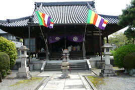 石畳の先に2つの石灯籠と奥に2本の仏旗が立っている興福寺を正面からうつした写真
