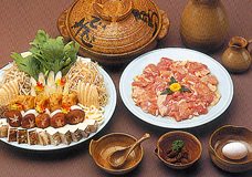 土鍋とお皿に盛られた鶏肉、大皿いっぱいのキノコや野菜、豆腐の写真