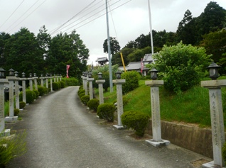 灯籠が道の両端にずらりと並んでいるコンクリートの参道の写真