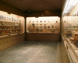 部屋の壁3面のガラス張りの中に格子状の棚があり、土器がたくさん展示されている写真