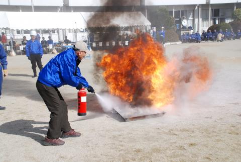燃えているものを消火器で消火する訓練を行っている写真