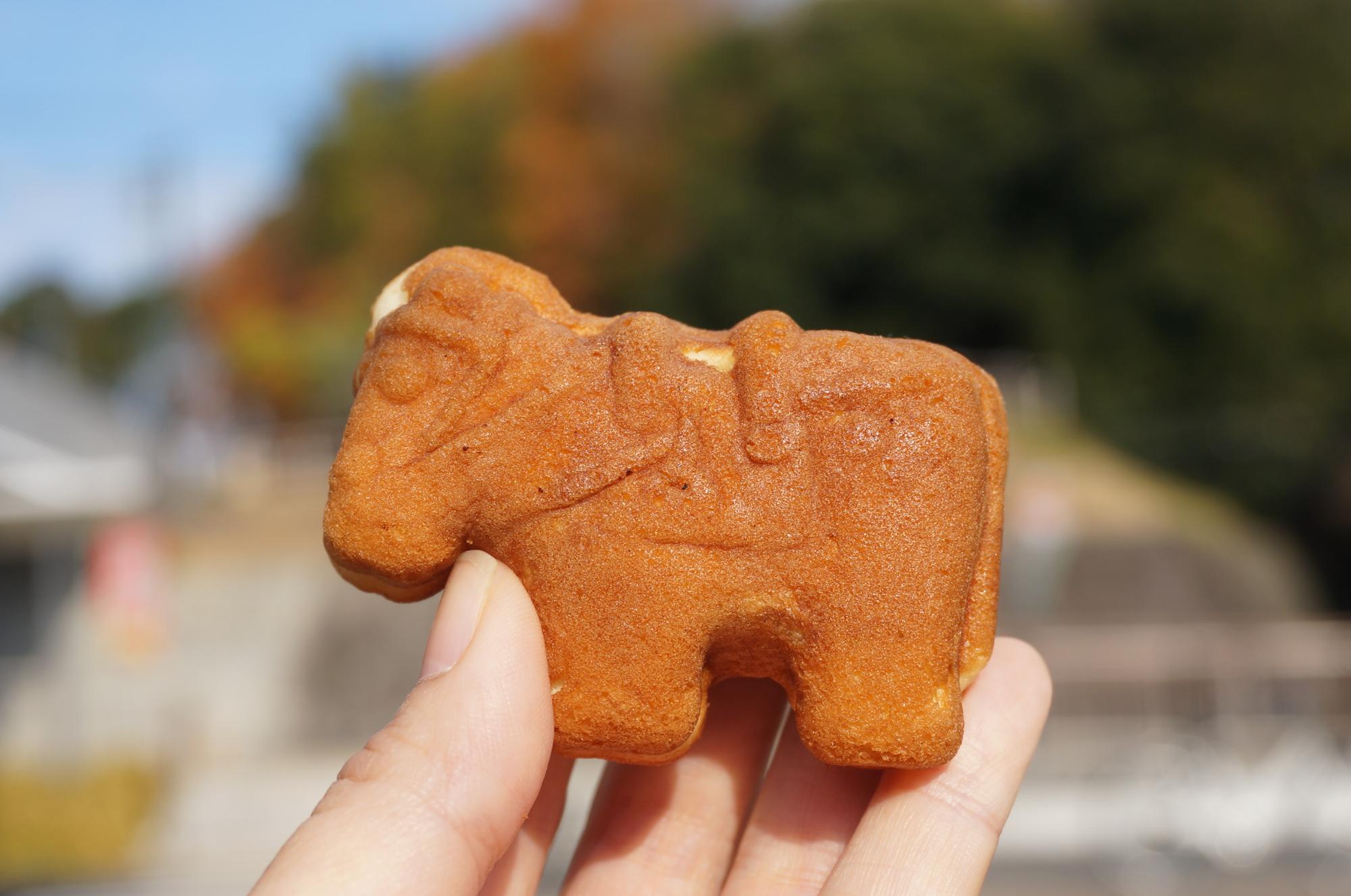 馬の形に焼かれたカステラ生地のまんじゅうを指先で持っている様子